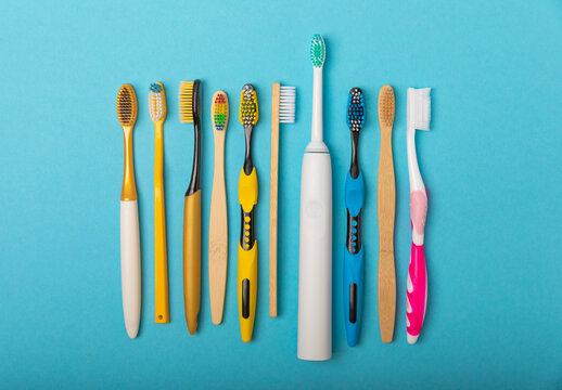 Electric and manual toothbrushes on a blue background. View from above. Oral hygiene. Ordinary toothbrush, eco and electric toothbrush. Oral hygiene. Oral Care Kit. Dentist concept. Dental care. 