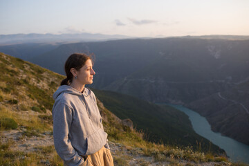 Naklejka na ściany i meble harmony with nature. person contemplates. girl looks at sunset in mountains