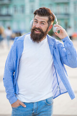 glad man hipster in music headphones in the street. photo of man hipster in music headphones