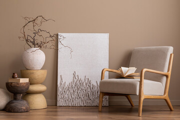 Creative composition of cozy living room interior with mock up poster frame, gray armchair, wooden coffee table, books, vase with branch, beige wall and personal accessories. Home decor. Template.