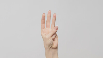 Hand gesture. Three number. Woman showing trio fingers up on light gray background.