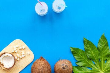 Coconut on green palm leaves with two glasses of fresh cocktail