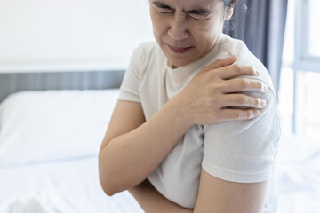 Asian middle aged woman suffering from shoulder pain,shoulder dislocation,aching numbness and weakness,tired female patient with Dislocated shoulder joint,discomfort caused by illness or injury