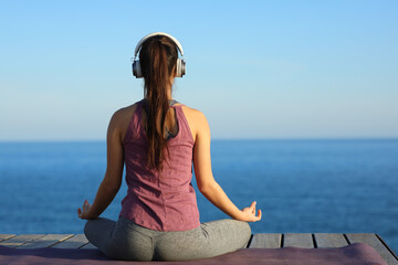 Back view of a yogi doing yoga with headphone