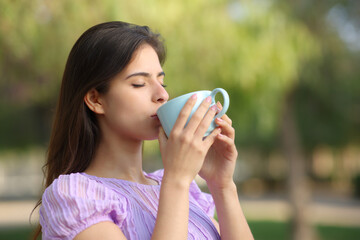 Woman drinking coffee in a park alone