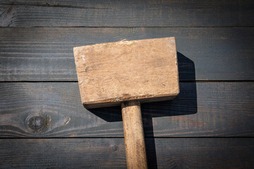 Old wooden carpenter's hammer on dark wood texture background