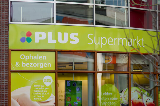 Arnhem, Netherlands - February 9, 2023: Logo of Plus supermarket store on the facade of the building in shopping street