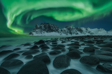 The dance of the Green Lady over Uttakleiv Beach. Winter night landscape with Northern Lights over...