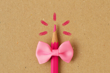 Pink pencil with pink bow tie on recycled paper background - Concept of women and creative thinking