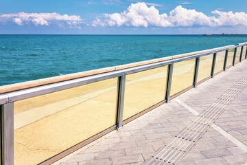 Fototapeta na wymiar Seaside with glass balustrade . Sidewalk on the sea shore