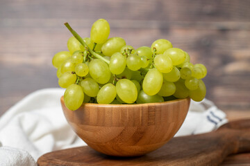 Green grapes in bowl. Organic farm products. Fresh bunch of grapes on wooden background. Close up