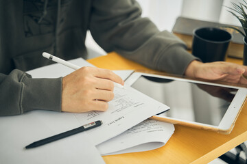a man holding a pen writing note on the table. or a student sitting and studying online while in the cafe home or workplace..