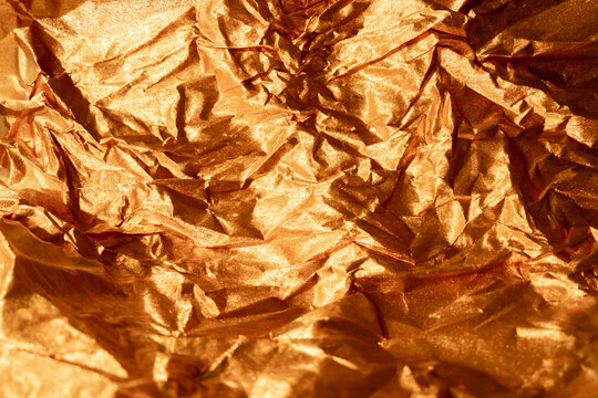Creased foil texture metallic background. Crumpled overlay. Golden shiny shimmering distressed wrinkled film abstract surface with free space.