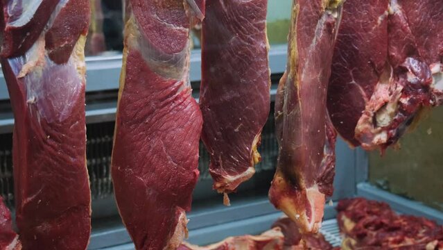 Close up of raw meat in the food market. Lamb carcasses hanging on hooks in a meat refrigerator. Beef tenderloin in a fridge