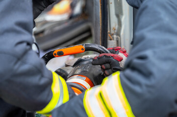 Fototapeta na wymiar Firefighters using hydraulic tools during a rescue operation training. Rescuers unlock the passenger in car after accident. High quality photography.