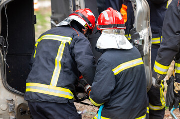 Firefighters using hydraulic tools during a rescue operation training. Rescuers unlock the passenger in car after accident. High quality photography.