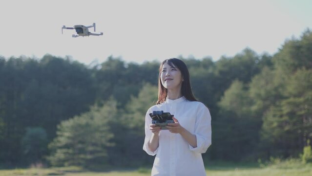 自然豊かな森の中でドローンの操縦をする日本人女性の夏のイメージ