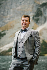 The man near the lake on the nature. Groom against the backdrop of a mountain landscape.