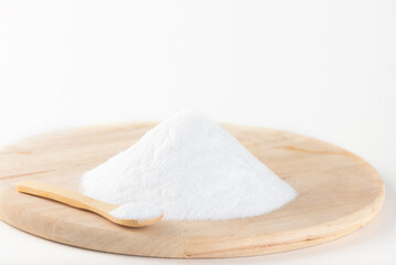 Pile of glucose or grape sugar in a spoon on a wooden board, white background.