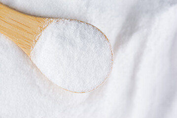 Glucose or grape sugar in a spoon on a wooden board, top view.