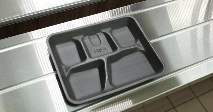 Empty foam lunch tray on metal shelf in schoot lunch line