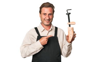 A middle-aged shoe maker smiling and pointing aside, showing something at blank space.