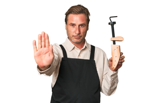 A middle-aged shoe maker standing with outstretched hand showing stop sign, preventing you.