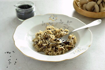 Basmati rice with brown mushrooms and sesame seeds on a gray stone background