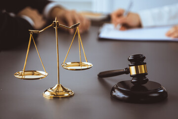 Focus shiny golden balanced scale on blurred background of lawyer working on desk at law firm...