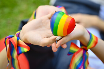 Closeup view of LGBT friends holding rainbow heart, celebrating gay pride, enjoying outdoor activities outdoor. LGBT community concept