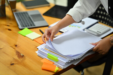 Cropped shot of female accountant working with annual financial report, preparing present at wooden office desk