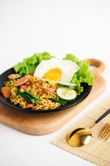 Tasty Fried instant noodle with sunny side up egg, sausage, and vegetable 