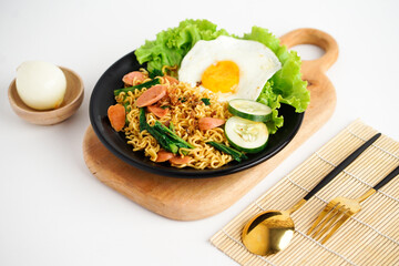 Tasty Fried instant noodle with sunny side up egg, sausage, and vegetable 