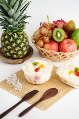 Indonesian salad buah keju or fruits salad mixed with other ingredients like grated cheese, yogurt, and liquid milk. Served in plastic cup on white background