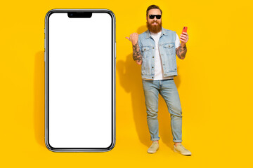 Photo of funny charming guy dressed denim vest sunglass pointing thumb modern gadget empty space...