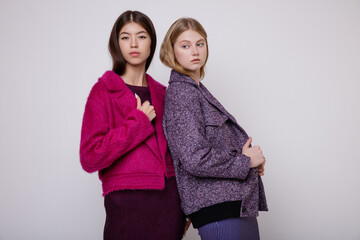 Two fashion models in pink fuchsia and blue dress, jacket. Beautiful young woman. Studio shot,...