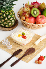 Obraz na płótnie Canvas Indonesian salad buah keju or fruits salad mixed with other ingredients like grated cheese, yogurt, and liquid milk. Served in plastic cup on white background