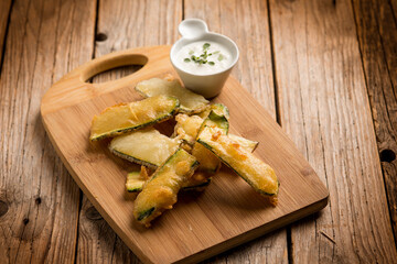 tempura zucchini with sauce over wood board