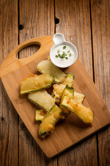 tempura zucchini with sauce over wood board