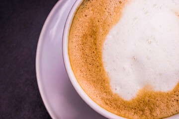 Hot Cappuccino with white cup on black wood table, top view
