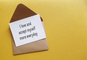 Card in envelope on yellow copy space background with message - I accept and love myself more...