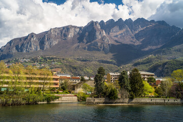 Fototapeta na wymiar Buildings of the city of Lecco on the banks of the river Adda. Bridges and an island with mountains in the background