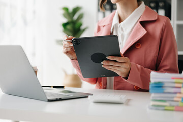 Hands of woman using mobile phone in modern office with laptop and digital tablet at office