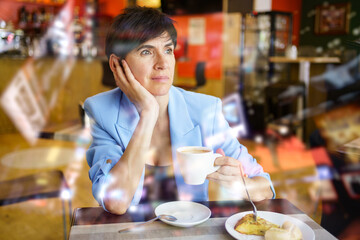 Wistful lady drinking coffee in cafeteria