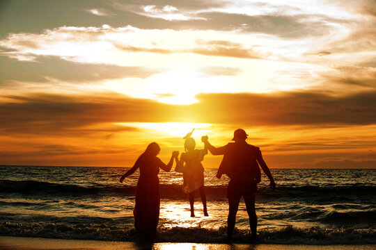 silhouette of a family walking on the beach at the sunset time. Concept of friendly family.