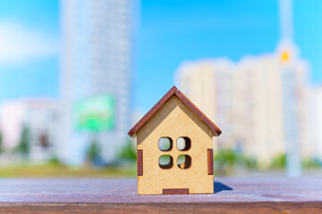 Tiny Wooden House Model Set against a Cityscape Backdrop