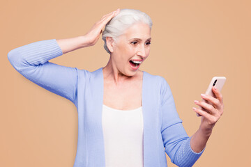 Grey haired old happy excited woman wearing casual, reading notification about winning, opened mouth. Isolated over violet purple background