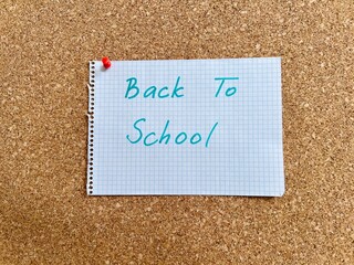 Back to school hand written text on notepad paper sheet and pinned on cork board