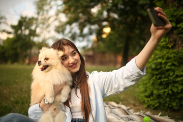 Caucasian girl student female pet owner taking selfie photo with dog, image on smart phone, having video call conversation with dog online in park