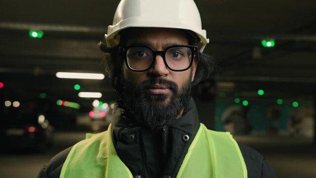 Muslim man Arabian worker Indian builder ethnic engineer serious looking at camera wearing hard hat helmet manufacture specialist mechanic contractor repairman inspecting construction work industry